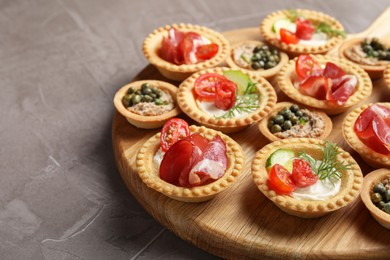 Photo of Delicious canapes with jamon, pate and dry smoked sausages on grey textured table