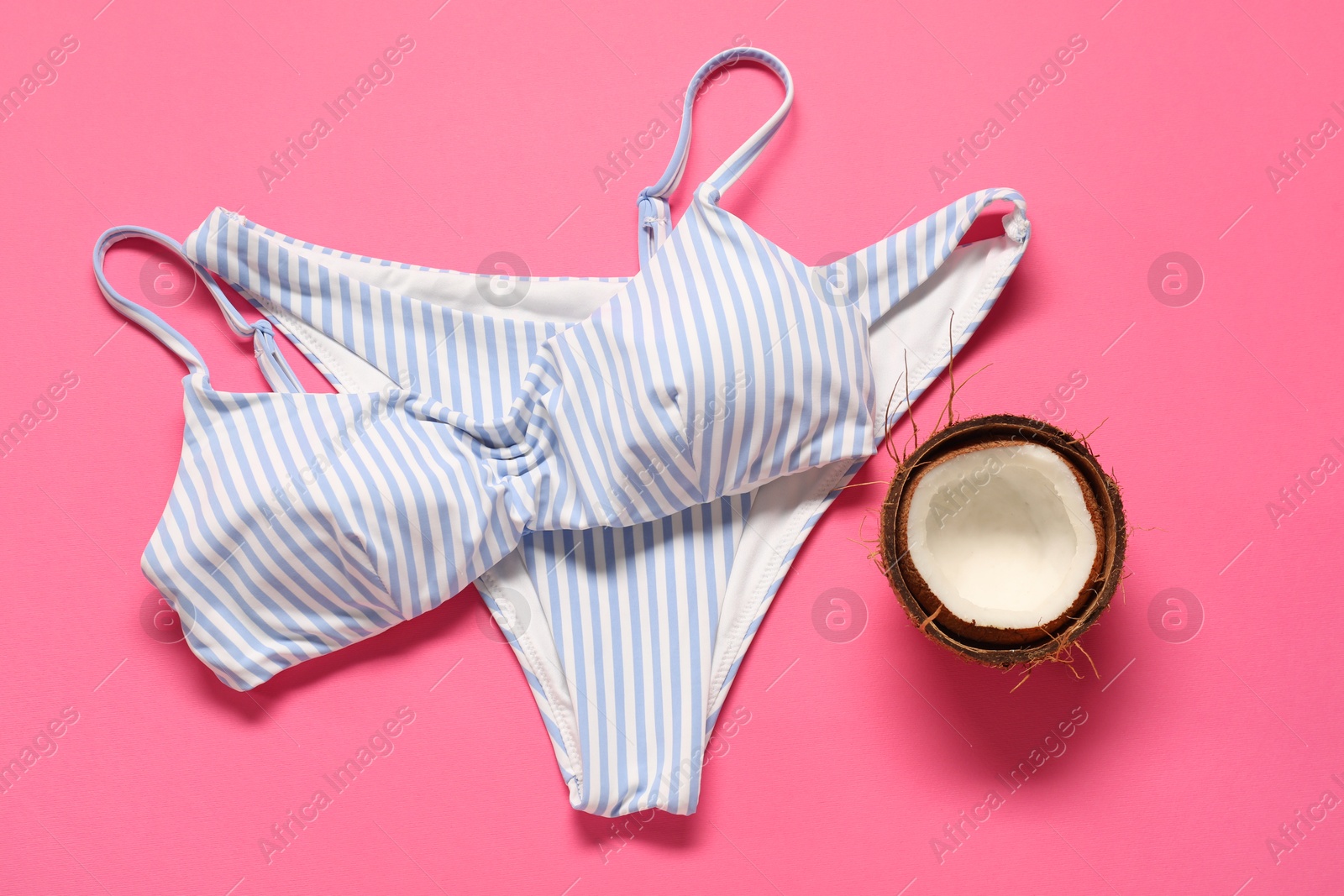 Photo of Striped swimsuit and coconut on pink background, flat lay