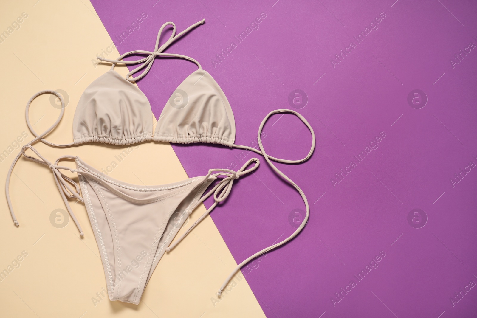 Photo of Beige swimsuit on color background, top view. Space for text