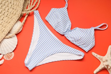 Photo of Striped swimsuit, bag, seashells and starfish on coral background, flat lay