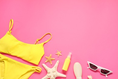 Flat lay composition with yellow swimsuit, sunscreen and sunglasses on pink background. Space for text