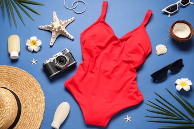 Flat lay composition with red swimsuit on blue background