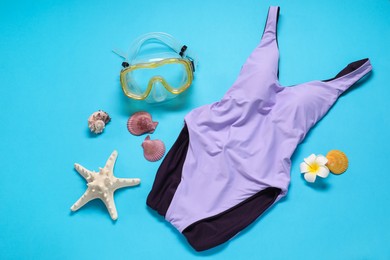 Violet swimsuit, diving mask and seashells on light blue background, flat lay