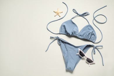 Photo of Beautiful swimsuit, sunglasses and starfish on light grey background, flat lay. Space for text