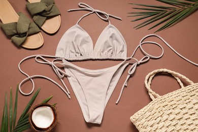 Flat lay composition with beautiful swimsuit, slippers and bag on brown background