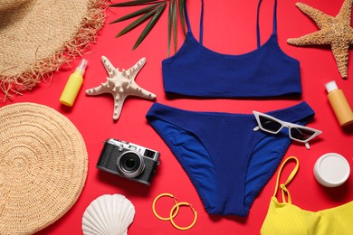 Photo of Flat lay composition with blue swimsuit, camera and bag on red background