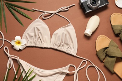 Flat lay composition with beautiful swimsuit and slippers on brown background