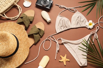 Photo of Flat lay composition with beautiful swimsuit and slippers on brown background