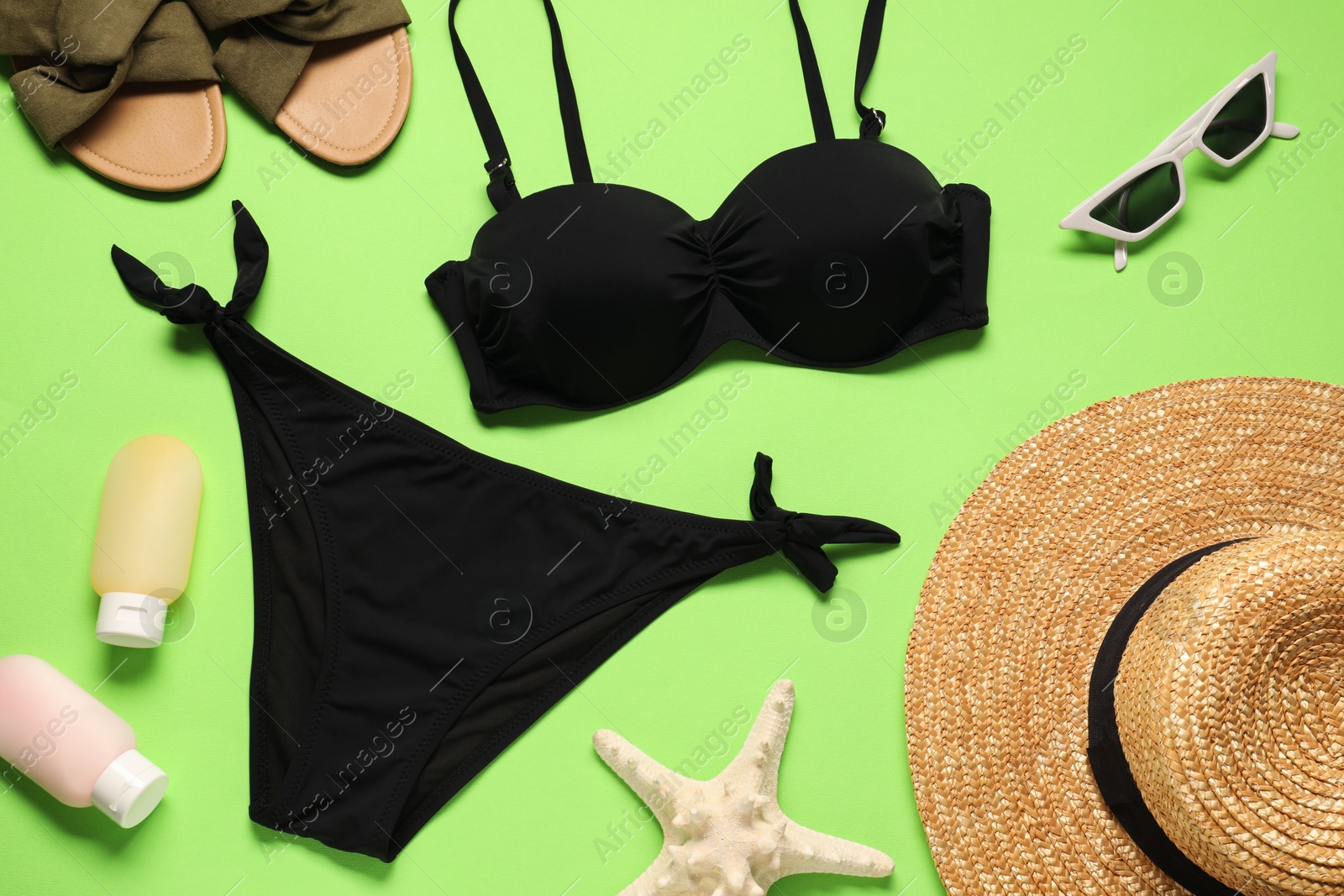 Photo of Flat lay composition with black swimsuit, sunglasses and hat on green background