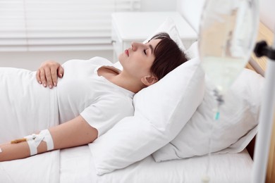 Young woman with intravenous drip in hospital bed