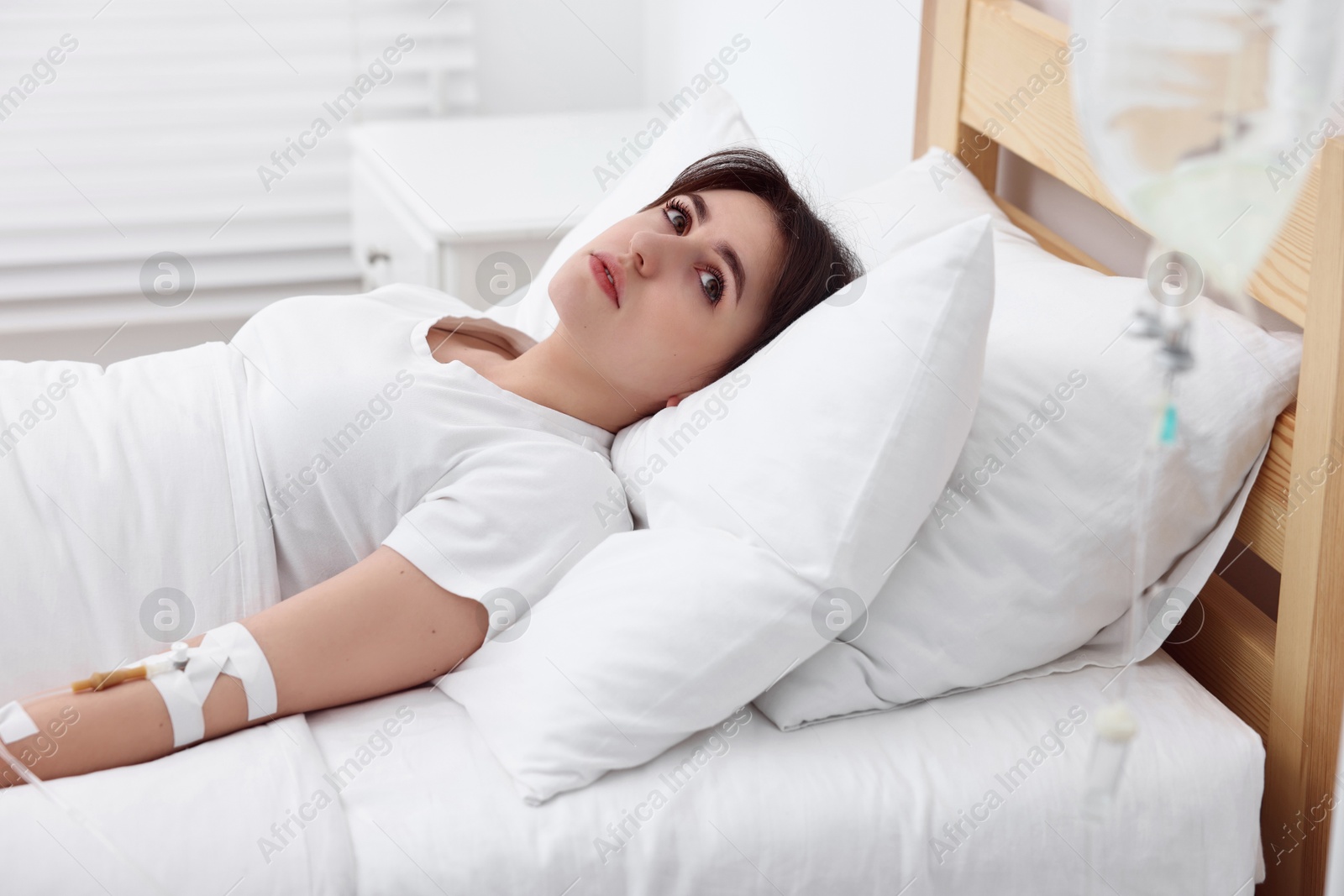 Photo of Young woman with intravenous drip in hospital bed