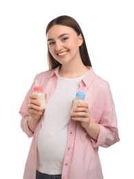 Photo of Expecting twins. Pregnant woman holding two bottles with milk on white background