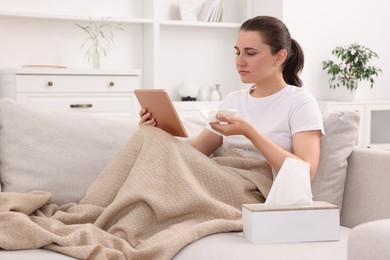 Sick woman having online consultation with doctor via tablet at home