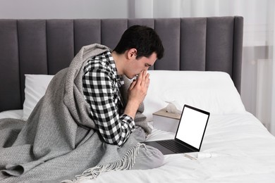 Sick man having online consultation with doctor via laptop at home