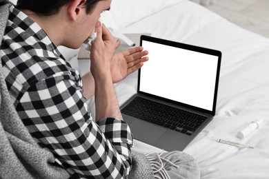 Sick man having online consultation with doctor via laptop at home