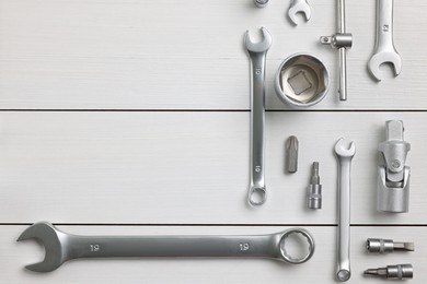 Photo of Auto mechanic's tools on white wooden table, flat lay. Space for text