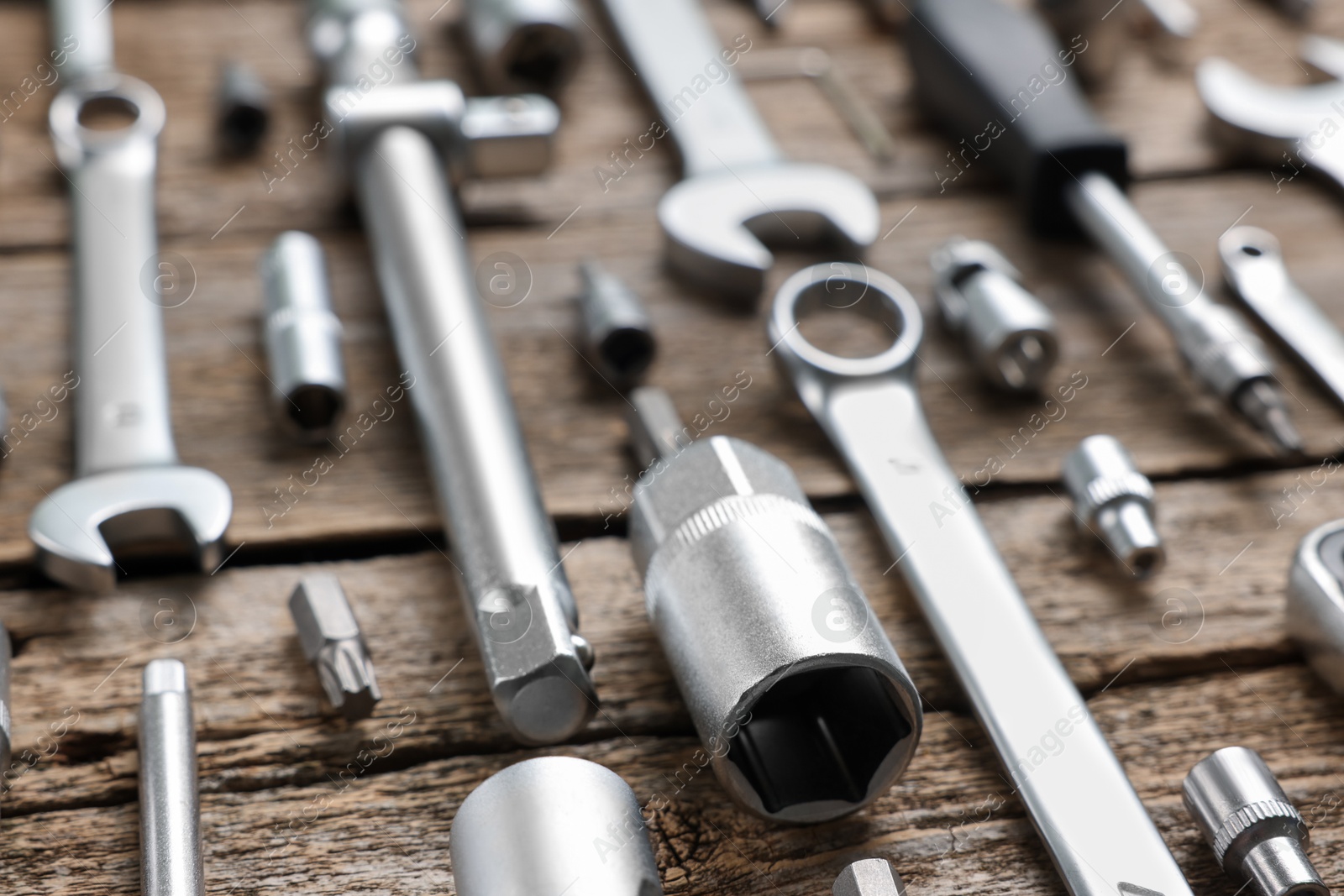 Photo of Different auto mechanic's tools on wooden table, closeup