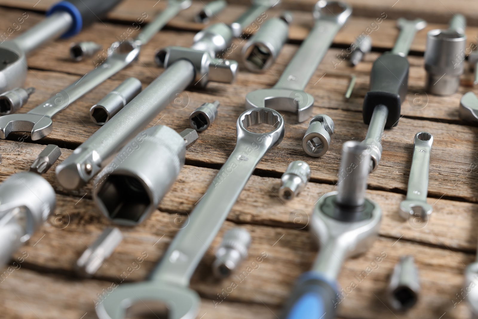 Photo of Different auto mechanic's tools on wooden table, closeup