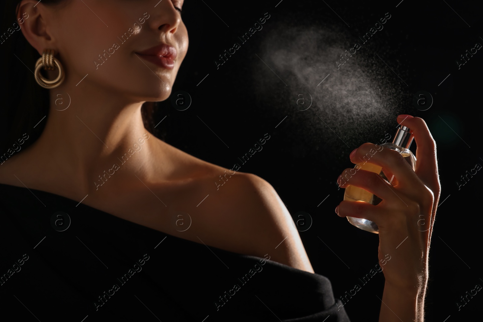 Photo of Woman spraying perfume on black background, closeup