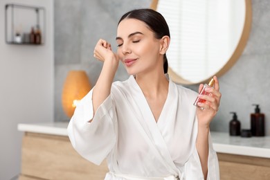 Beautiful woman smelling aromatic perfume in bathroom