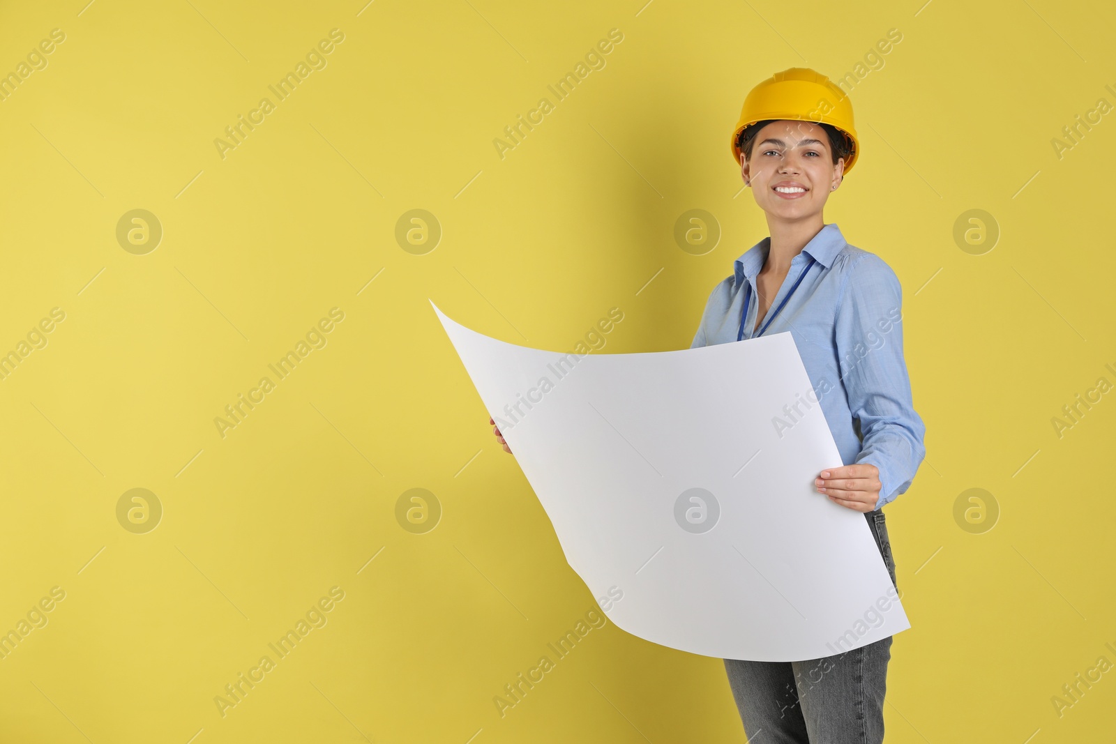 Photo of Engineer in hard hat with draft on yellow background, space for text