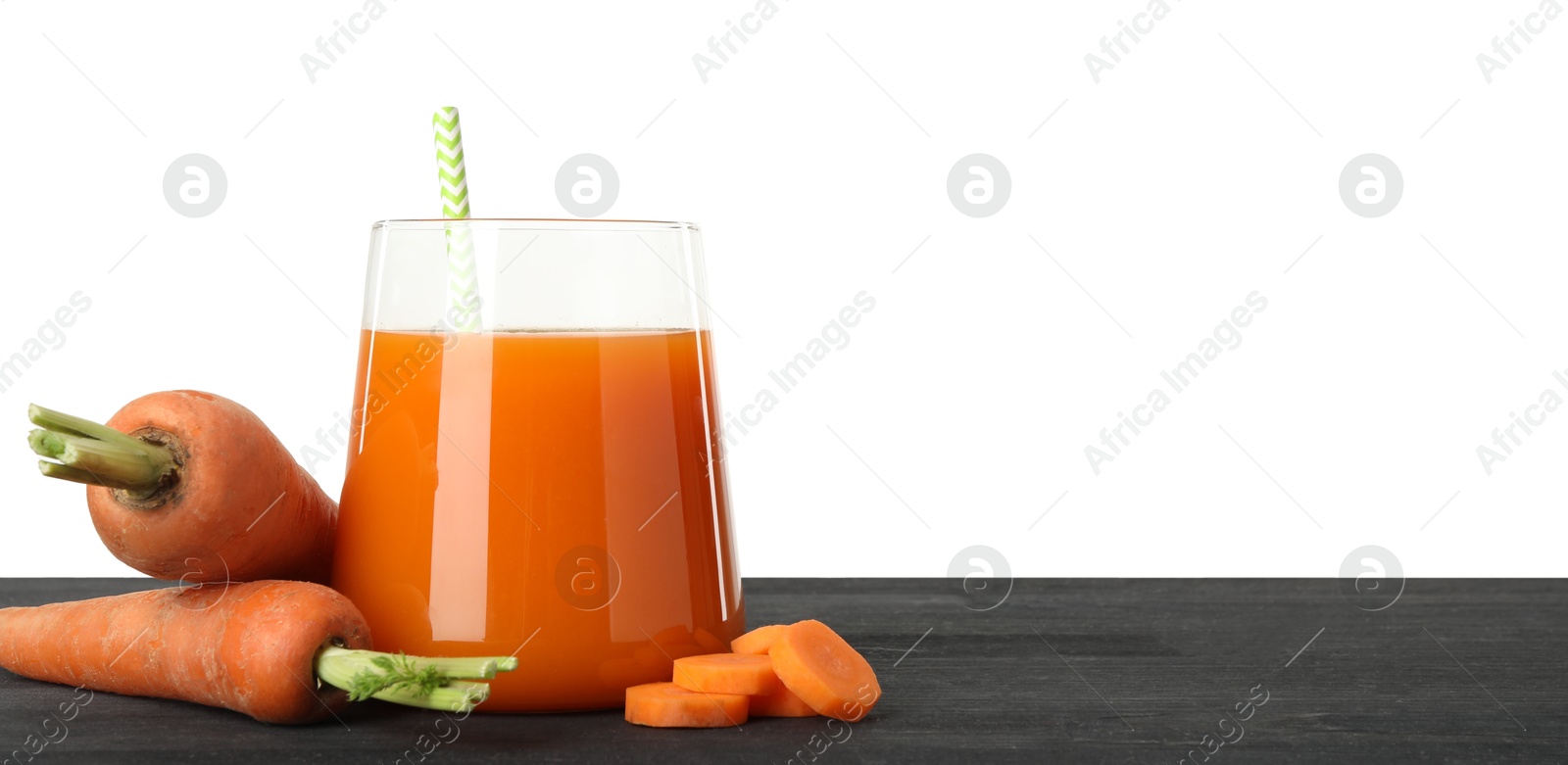 Photo of Fresh carrot juice in glass and vegetables on black wooden table against white background. Space for text