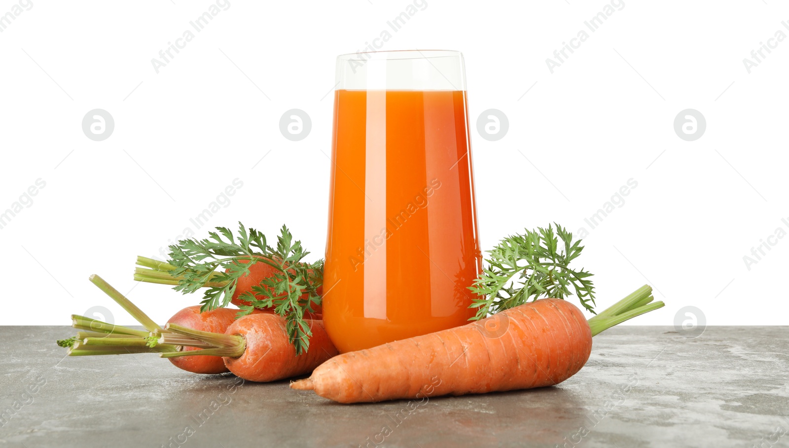 Photo of Fresh carrot juice in glass and vegetables on grey textured table against white background