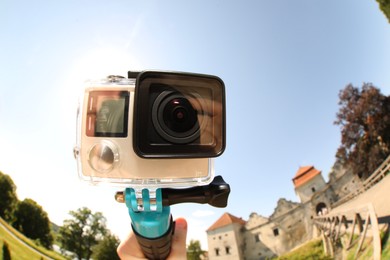 Man with modern action camera and monopod outdoors, closeup. Fisheye lens effect