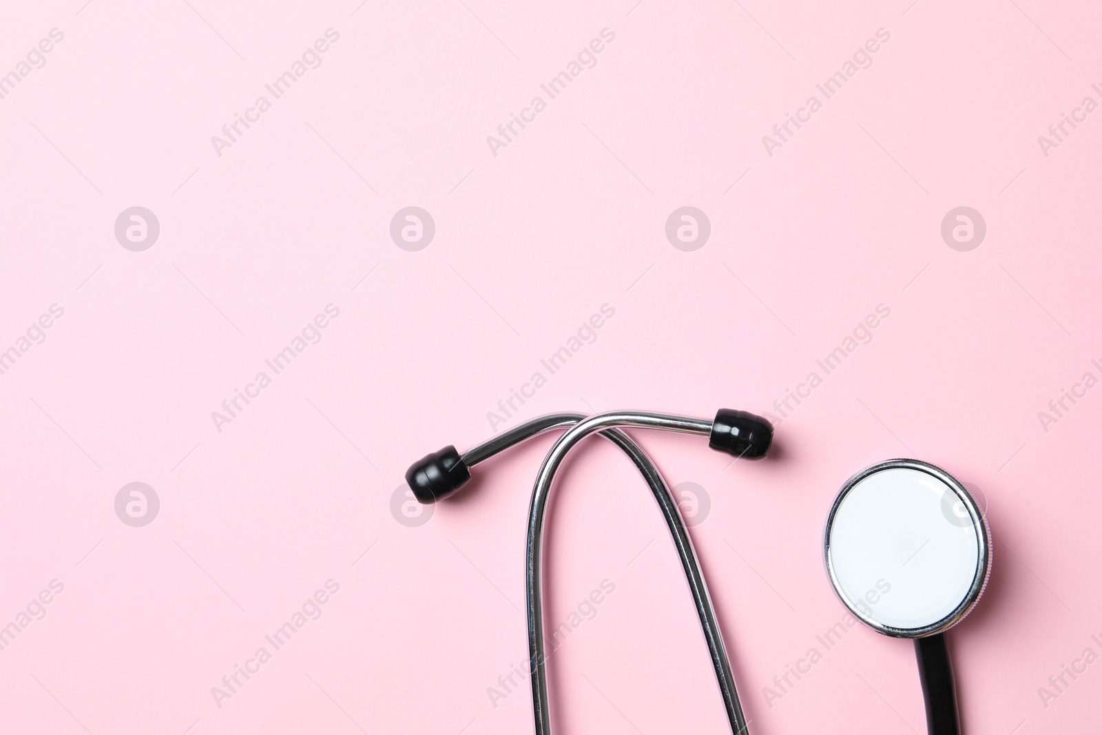 Photo of Stethoscope on pink background, top view. Space for text