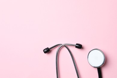 Photo of Stethoscope on pink background, top view. Space for text