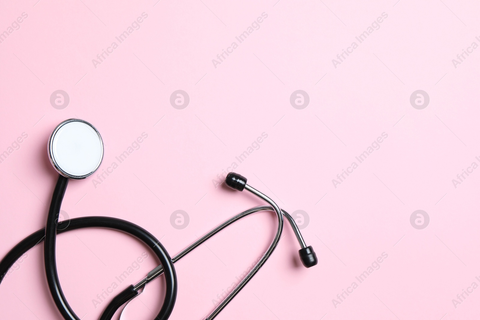 Photo of Stethoscope on pink background, top view. Space for text