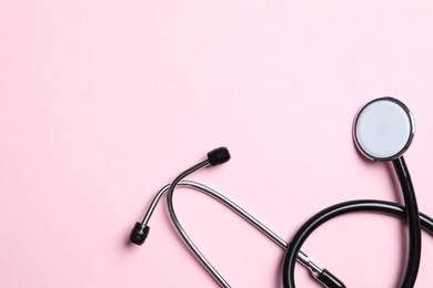 Photo of Stethoscope on pink background, top view. Space for text