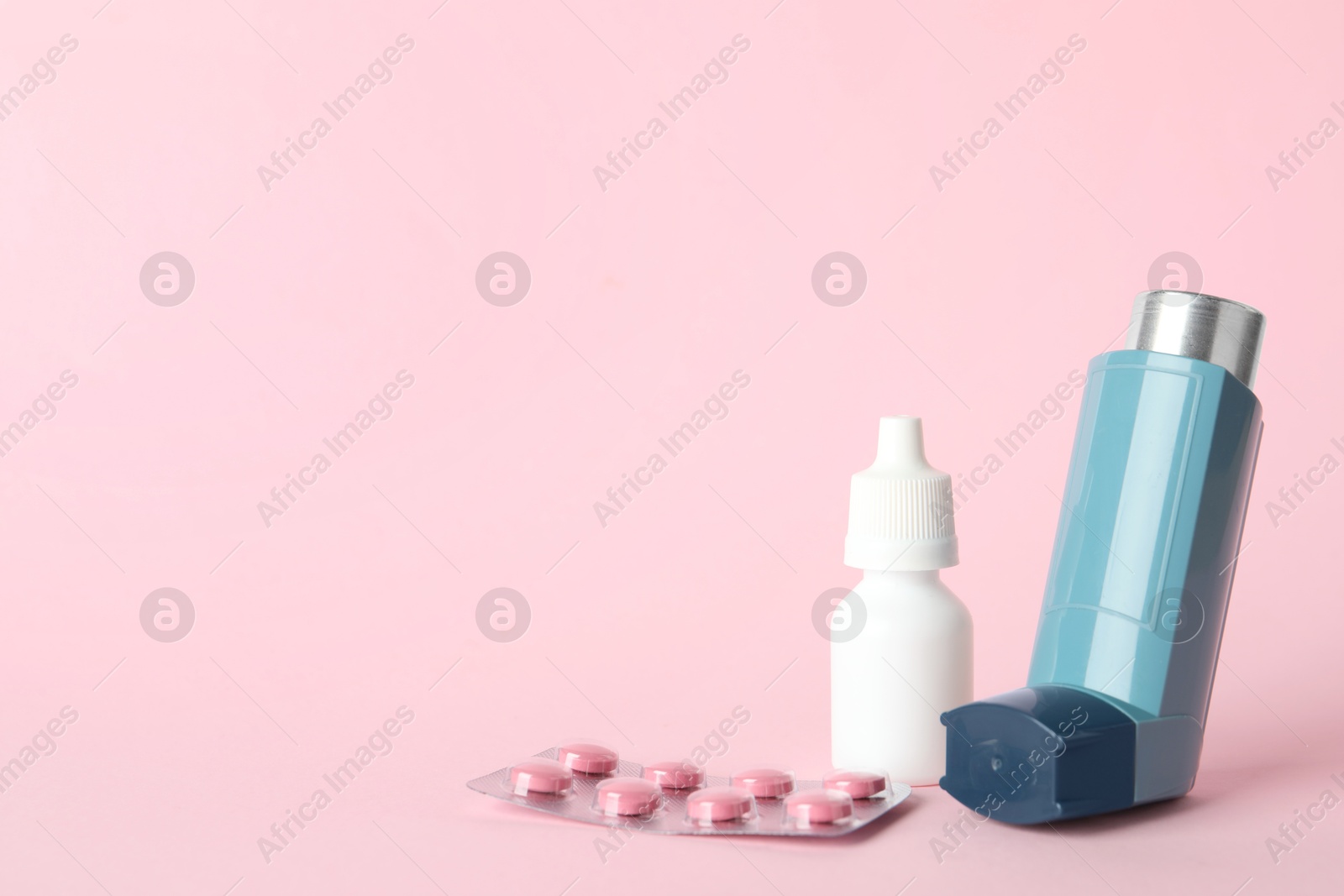 Photo of Different asthma medications on pink background, closeup. Space for text