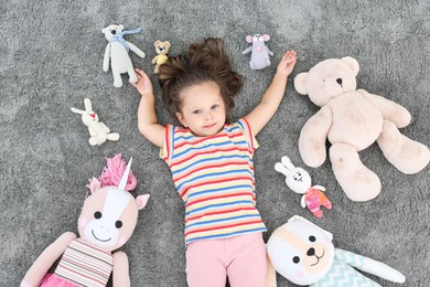 Cute little girl and soft toys on floor, top view