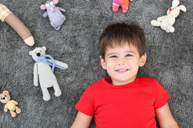 Photo of Cute little boy and soft toys on floor, top view