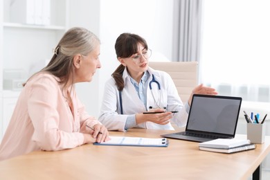 Photo of Lung disease. Doctor showing something on laptop to her patient in clinic