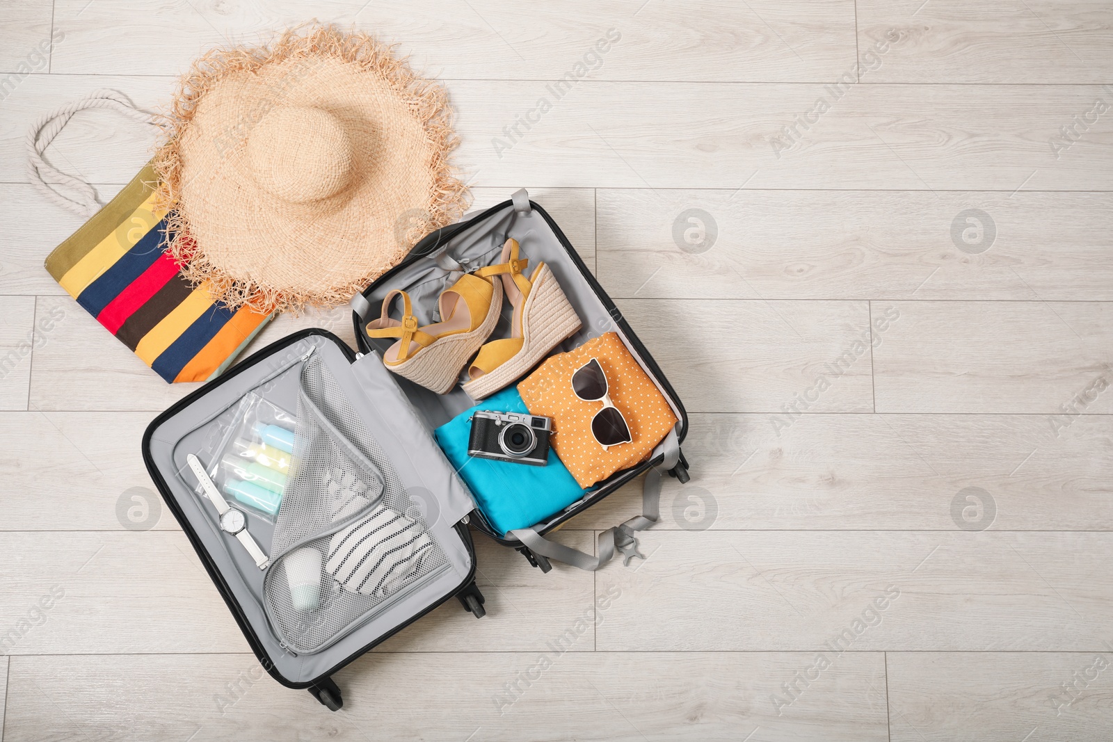 Photo of Open suitcase with traveler's belongings on floor, flat lay. Space for text