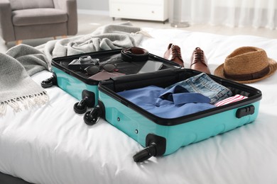 Open suitcase with traveler's belongings on bed