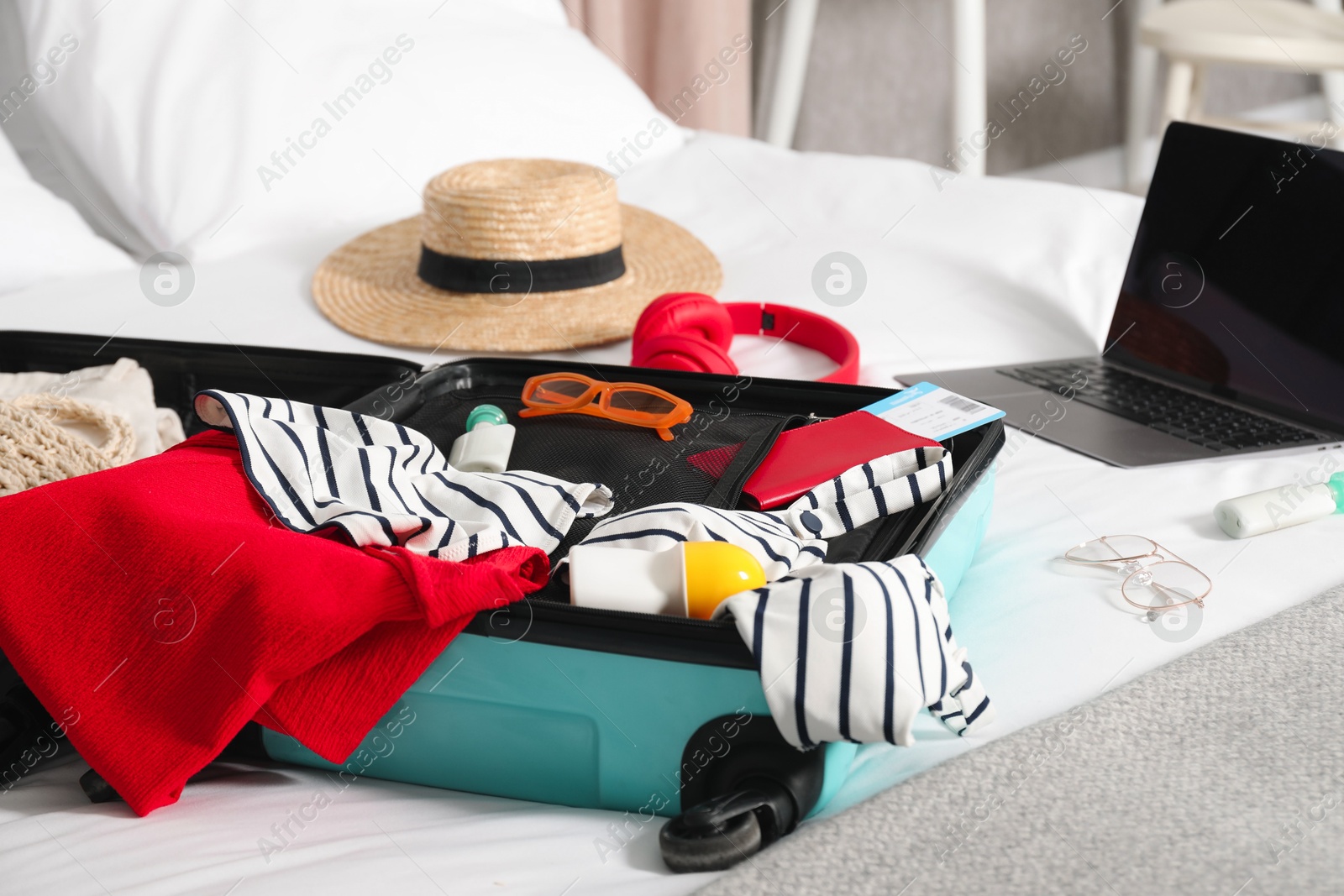 Photo of Open suitcase with traveler's belongings on bed, closeup