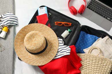 Photo of Open suitcase with traveler's belongings on bed, flat lay