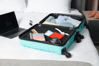 Photo of Open suitcase with traveler's belongings on bed