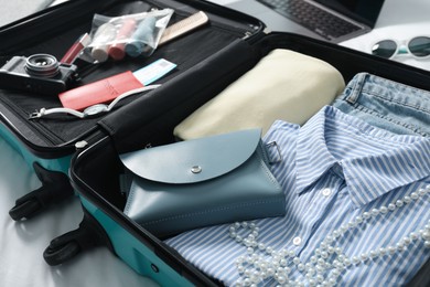 Photo of Open suitcase with traveler's belongings on bed, closeup