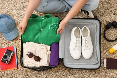 Photo of Man packing suitcase on floor at home, top view