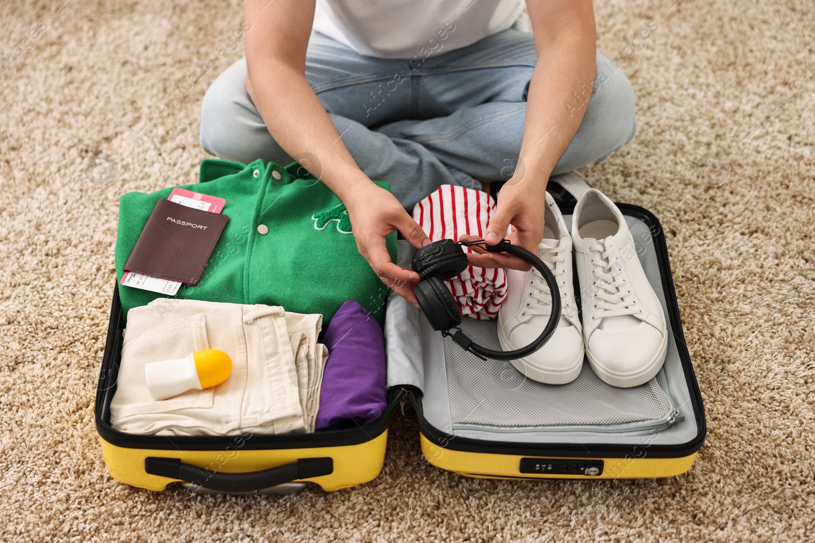 Photo of Man packing suitcase on floor at home, closeup