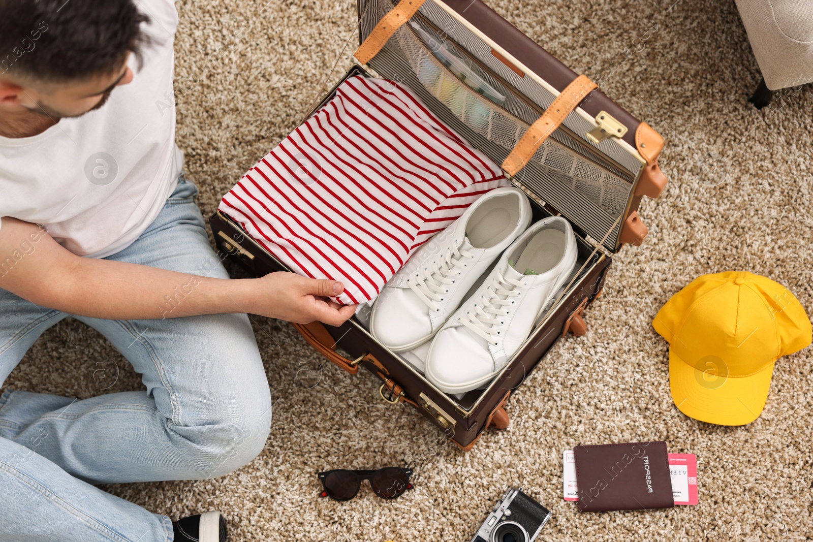 Photo of Man packing suitcase on floor at home, top view