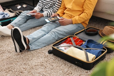 Couple with passports and tickets near suitcases on floor indoors, closeup