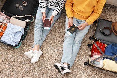 Couple with passports and tickets near suitcases on floor indoors, closeup