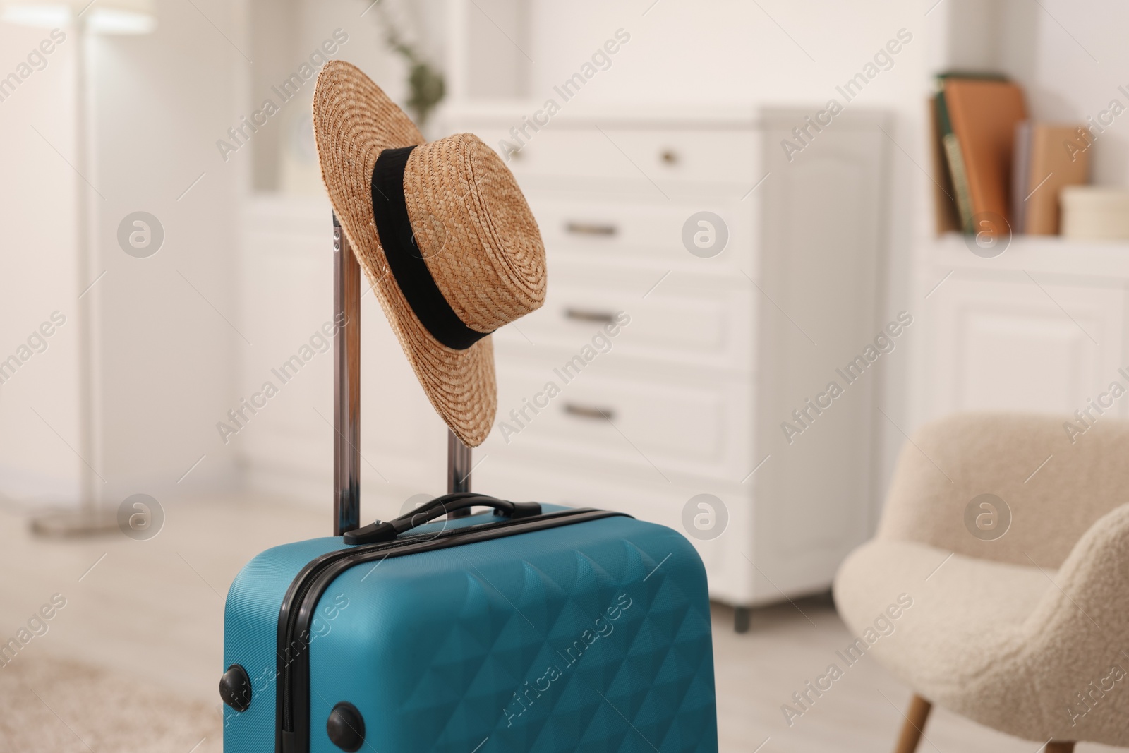 Photo of Light blue suitcase and straw hat indoors