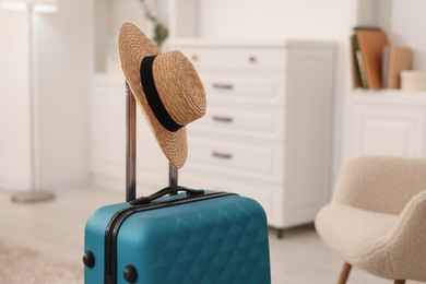 Light blue suitcase and straw hat indoors