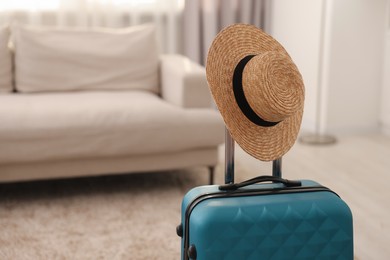 Photo of Light blue suitcase and straw hat indoors, space for text